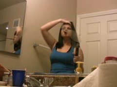 Pretty brunette babe straightens her hair in front of mirror clip