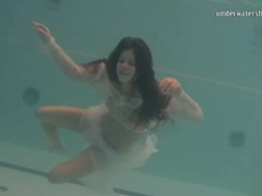 Young brunette swims in sheer white clothes